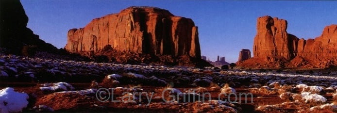 Panoramic photograph of red rock buttes dusted with snow at dawn