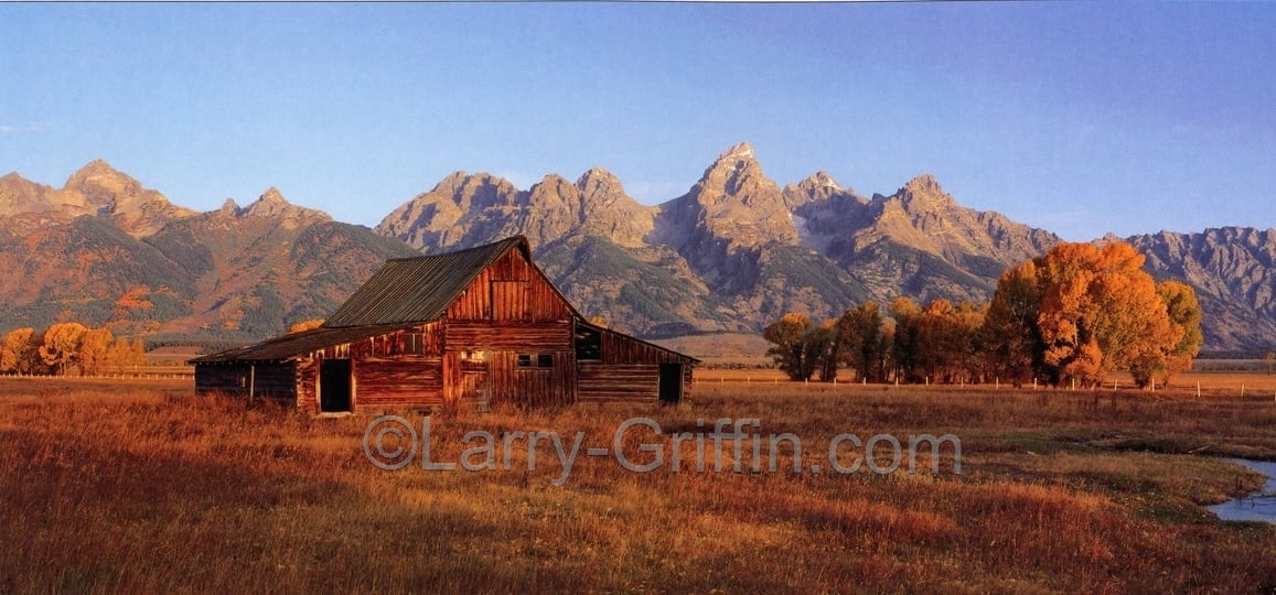 Panoramic photograph of an old barn beneath the Grand Teton range in autumn