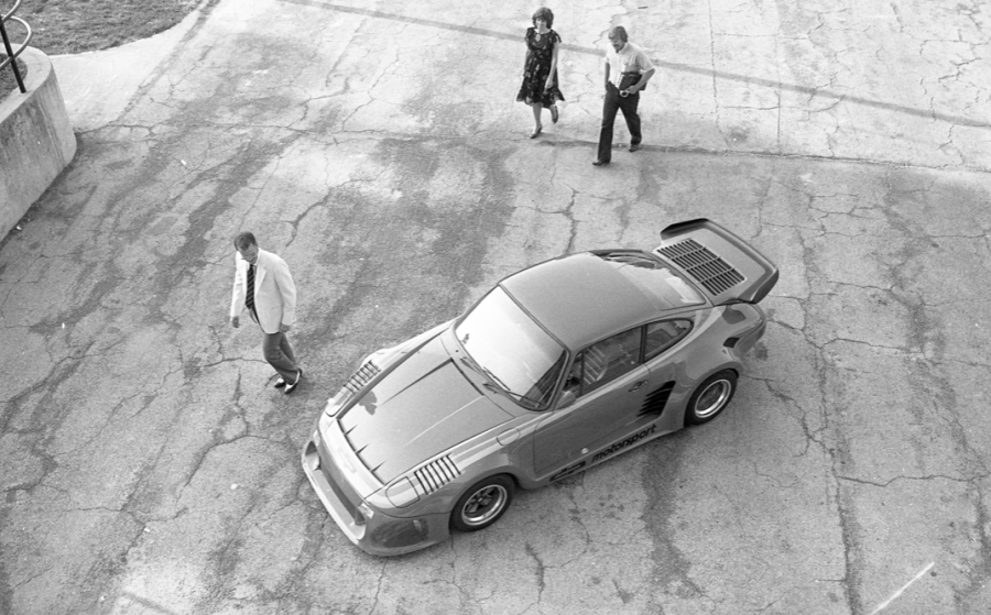 Overhead view of the Porsche 935 in a parking lot with onlookers