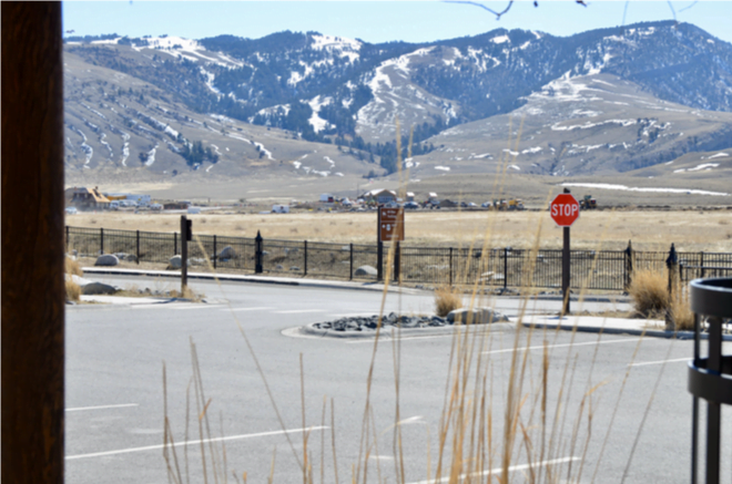 Parking area and stop sign beneath snow-streaked foothills