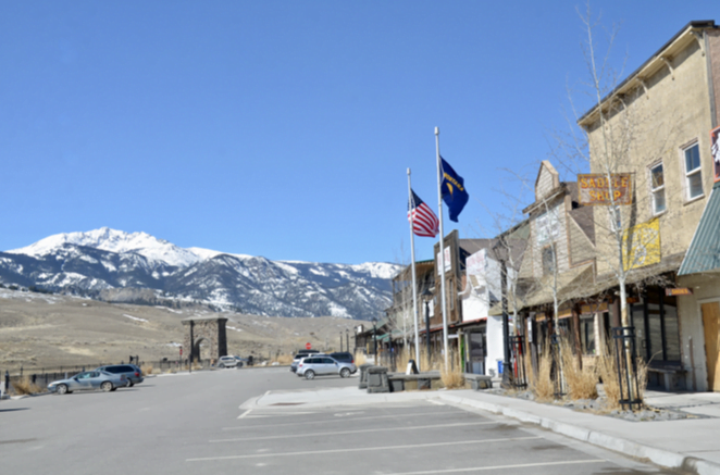 Gardiner main street with flags and a snow-capped peak in the distance