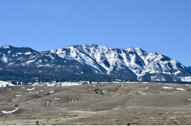 A long snow-streaked mountain range above open foothills