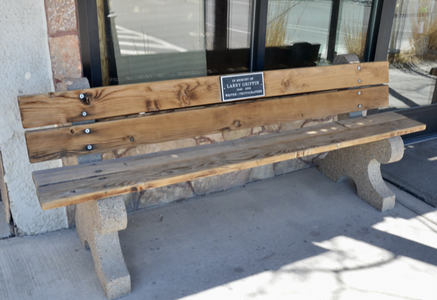 A wooden memorial bench for Larry Griffin on a sidewalk in Gardiner, Montana