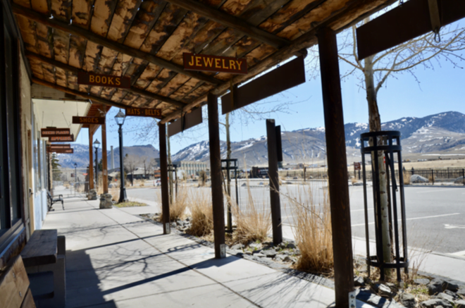 Wooden boardwalk with Books and Jewelry signs, mountains beyond